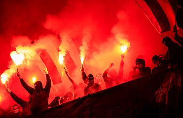 Image showing football hooligans with mask holding torches in fire