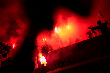 Image showing football hooligans with mask holding torches in fire