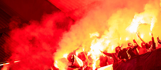 Image showing football hooligans with mask holding torches in fire