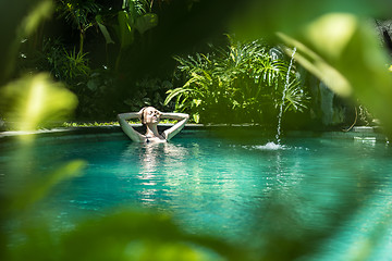 Image showing Sensual young woman relaxing in outdoor spa infinity swimming pool surrounded with lush tropical greenery of Ubud, Bali.