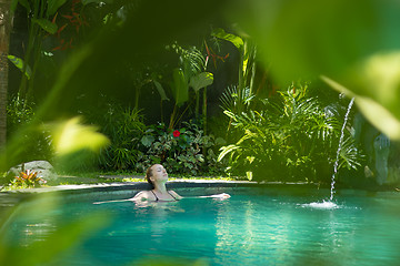 Image showing Sensual young woman relaxing in outdoor spa infinity swimming pool surrounded with lush tropical greenery of Ubud, Bali.