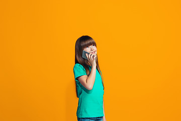 Image showing The happy teen girl standing and smiling against orange background.