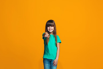 Image showing The happy teen girl pointing to you, half length closeup portrait on orange background.