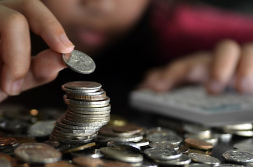 Image showing Coin piles and hand holding coin