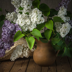 Image showing Still-life with a bouquet of lilacs and a straw hat