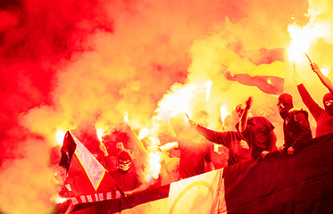 Image showing football hooligans with mask holding torches in fire