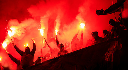 Image showing football hooligans with mask holding torches in fire