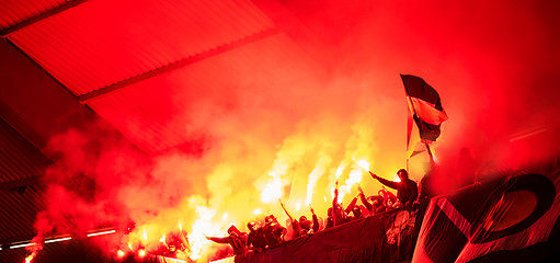 Image showing football hooligans with mask holding torches in fire