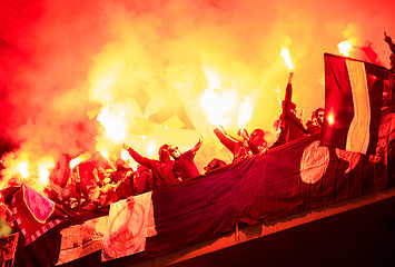 Image showing football hooligans with mask holding torches in fire