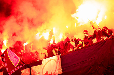 Image showing football hooligans with mask holding torches in fire