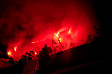 Image showing football hooligans with mask holding torches in fire