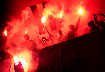 Image showing football hooligans with mask holding torches in fire