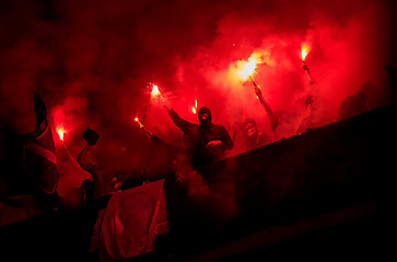 Image showing football hooligans with mask holding torches in fire