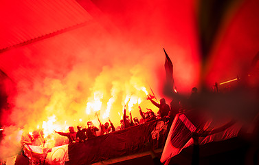 Image showing football hooligans with mask holding torches in fire