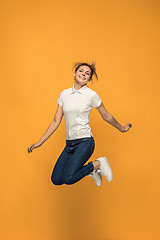 Image showing Freedom in moving. Pretty young woman jumping against orange background