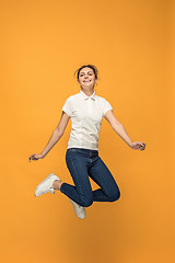 Image showing Freedom in moving. Pretty young woman jumping against orange background