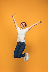 Image showing Freedom in moving. Pretty young woman jumping against orange background