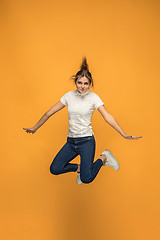 Image showing Freedom in moving. Pretty young woman jumping against orange background