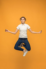 Image showing Freedom in moving. Pretty young woman jumping against orange background