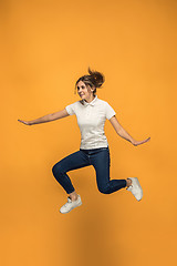 Image showing Freedom in moving. Pretty young woman jumping against orange background