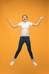 Image showing Freedom in moving. Pretty young woman jumping against orange background