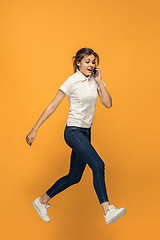 Image showing Full length of pretty young woman with mobile phone while jumping