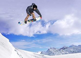 Image showing Snowboarder jumping through air with blue sky in background