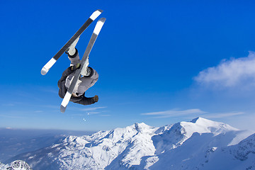 Image showing Extreme Jumping skier at jump above mountains at sunny day