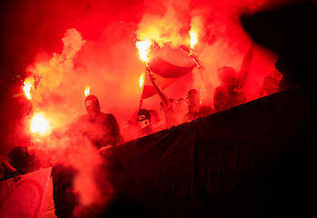 Image showing football hooligans with mask holding torches in fire