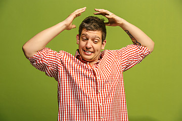 Image showing Beautiful male half-length portrait isolated on blue studio backgroud. The young emotional surprised man