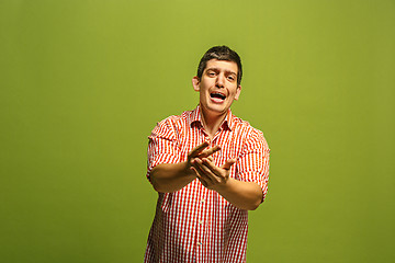 Image showing Beautiful male half-length portrait isolated on green studio backgroud. The young emotional surprised man