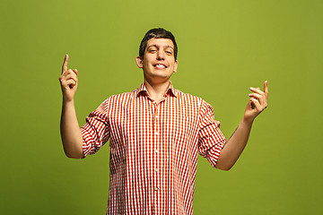 Image showing Beautiful male half-length portrait isolated on green studio backgroud. The young emotional surprised man