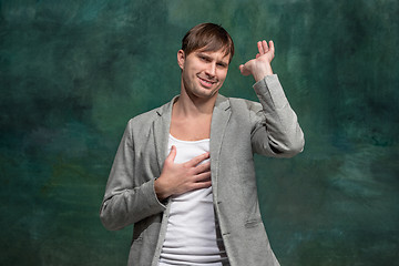 Image showing Beautiful male half-length portrait at studio backgroud. The young emotional surprised man