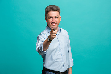 Image showing The happy business man point you and want you, half length closeup portrait on blue background.