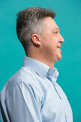 Image showing The happy businessman standing and smiling against blue background.