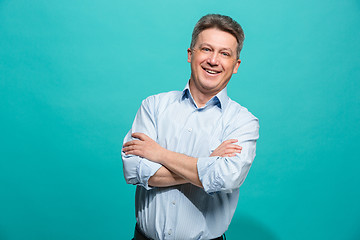 Image showing The happy businessman standing and smiling against blue background.