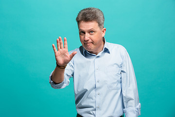 Image showing Beautiful male half-length portrait isolated on blue studio backgroud. The senior emotional surprised man