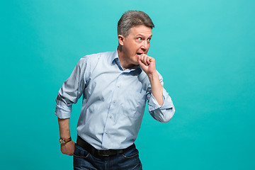 Image showing Beautiful male half-length portrait isolated on blue studio backgroud. The senior emotional surprised man