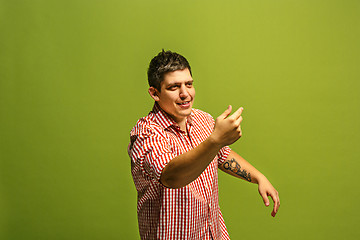 Image showing Isolated on green young casual man shouting at studio