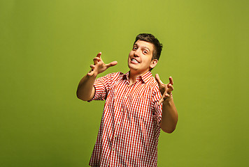 Image showing The young emotional angry man screaming on green studio background
