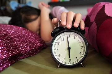 Image showing Pretty girl sleeping on the background of a retro alarm clock