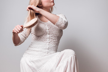 Image showing Lady in white brushing her blond hair