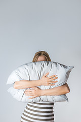 Image showing Young woman hugging a gray pillow
