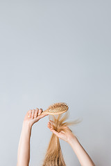 Image showing Brushing blond hair with a wooden hairbrush