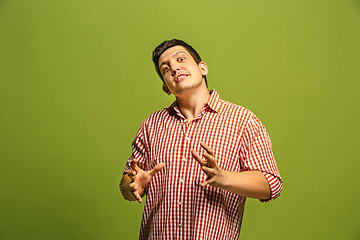 Image showing The young emotional angry man screaming on green studio background