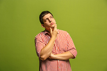 Image showing Let me think. Doubtful pensive man with thoughtful expression making choice against green background