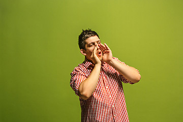 Image showing Isolated on green young casual man shouting at studio