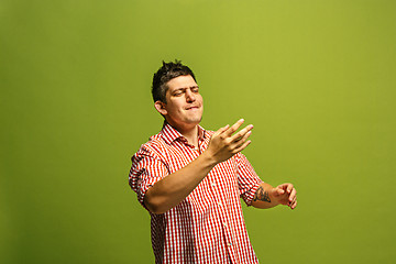 Image showing Isolated on green young casual man shouting at studio