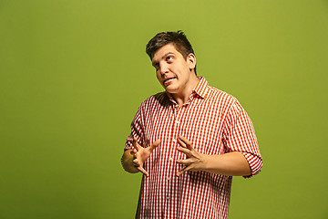 Image showing The young emotional angry man screaming on green studio background