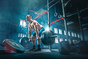 Image showing Fit young man lifting barbells working out in a gym